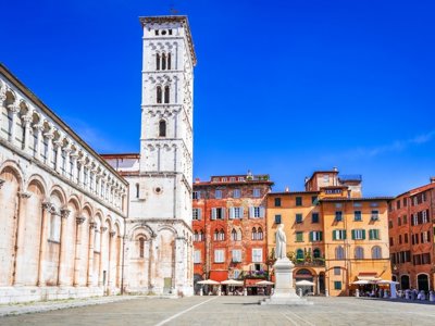 Fietser op landweg tussen cipressen en glooiende heuvels in Toscane.