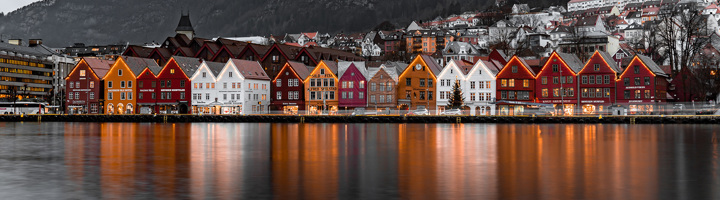 Gekleurde houten huizen aan de Bryggen-kade in Bergen, Noorwegen, met weerspiegeling in het water.