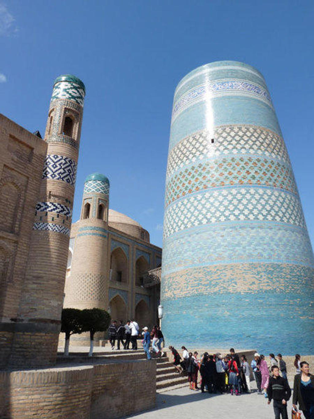 Turquoise betegelde minaretten en moskee in Khiva, Oezbekistan, tijdens een groepsrondreis langs de Zijderoute.