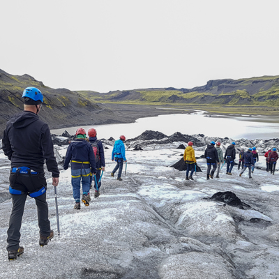 Groep wandelt met helm en stijgijzers over een gletsjer tijdens een 22-35ers reis in IJsland.