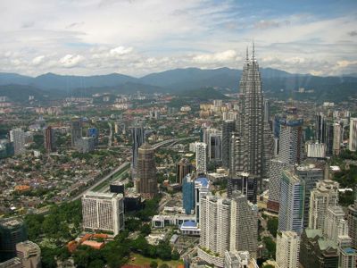 Skyline van Kuala Lumpur met de Petronas Twin Towers en bergen op de achtergrond.