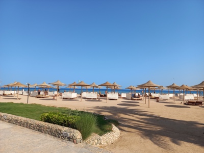 Strand aan de Rode Zee met rieten parasols en ligbedden tijdens Route Egypte.