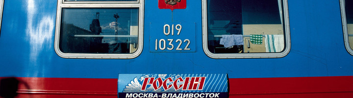 Blauwe Trans-Siberië-treinwagon met ramen en routebord Moskou–Vladivostok.