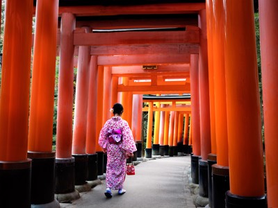 Vrouw in kimono loopt door de rode torii-poorten van Fushimi Inari-taisha in Kyoto, Japan.