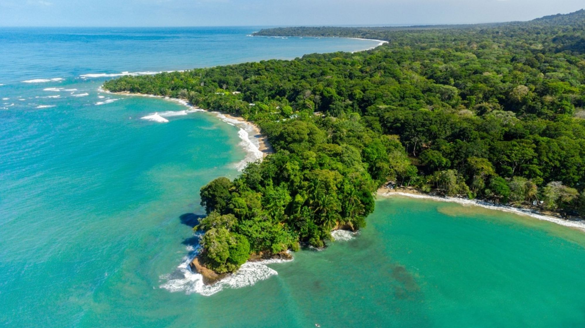 een tropische kustlijn met regenwoud en turquoise zee in Costa Rica.