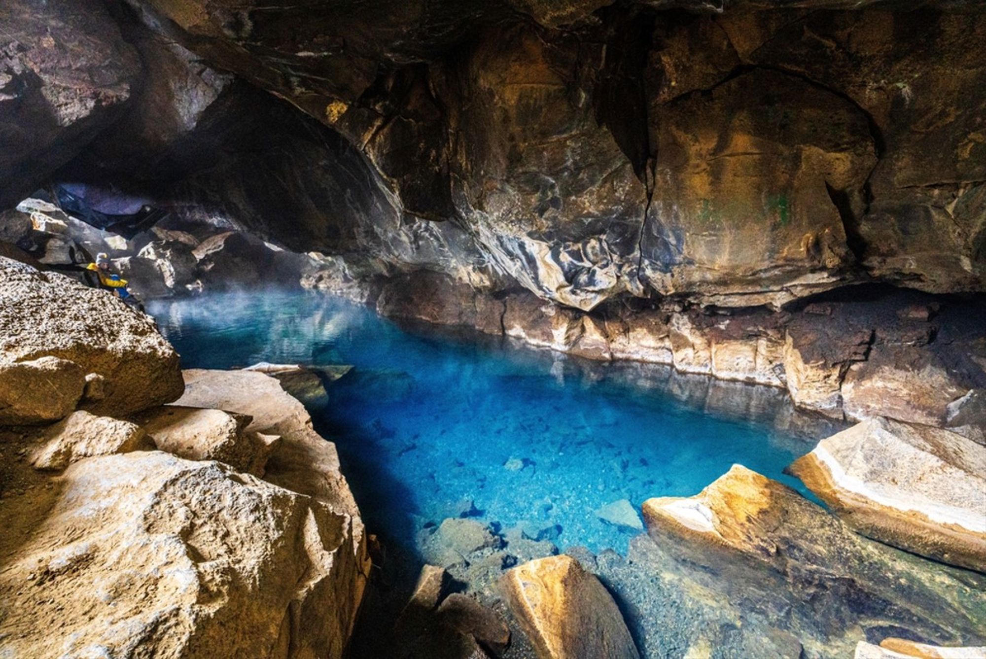 Kristalhelder blauw geothermisch water in een lavagrot in IJsland.