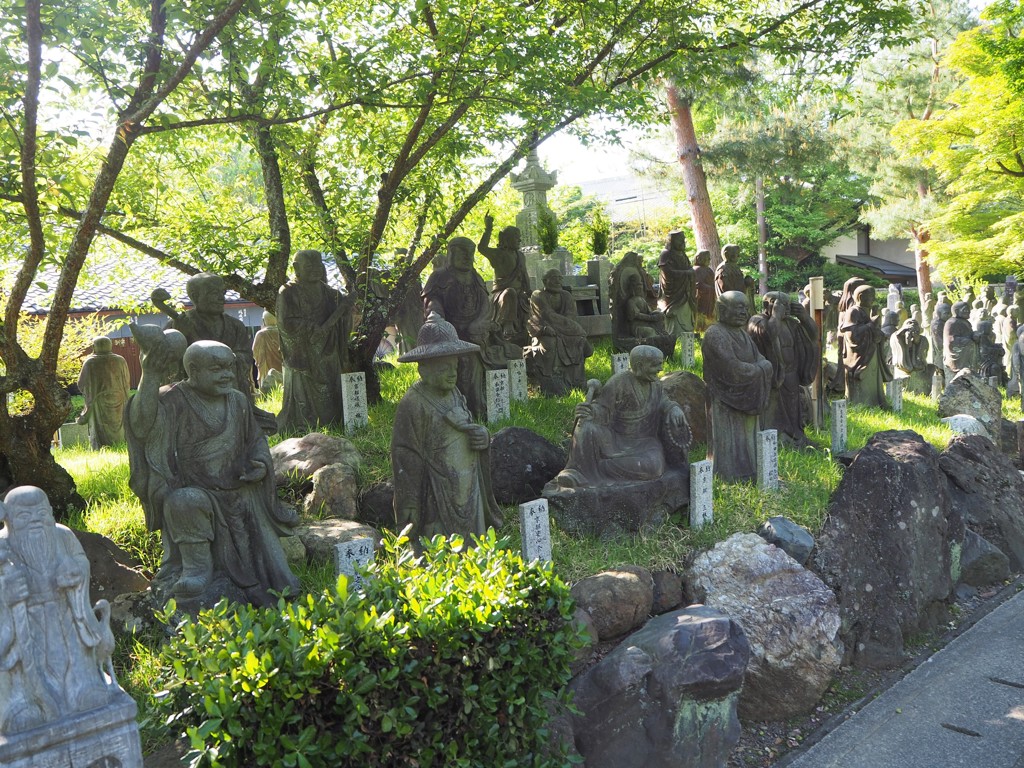 Japanse boeddhabeelden in een groene tempeltuin tijdens een groepsrondreis Japan.