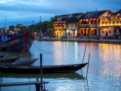Avondzicht op de rivier in Hoi An met houten boten en verlichte huizen langs de kade, Vietnam.