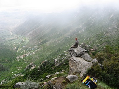 Wandelaar op rots met uitzicht over een groene bergvallei tijdens de Route Tibet en Nepal.
