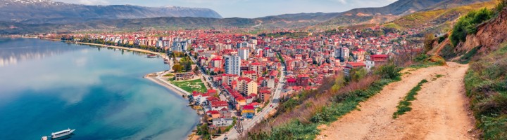 Uitzicht op het Meer van Ohrid met stad aan de kust, bergen op de achtergrond en wandelpad langs de heuvel.