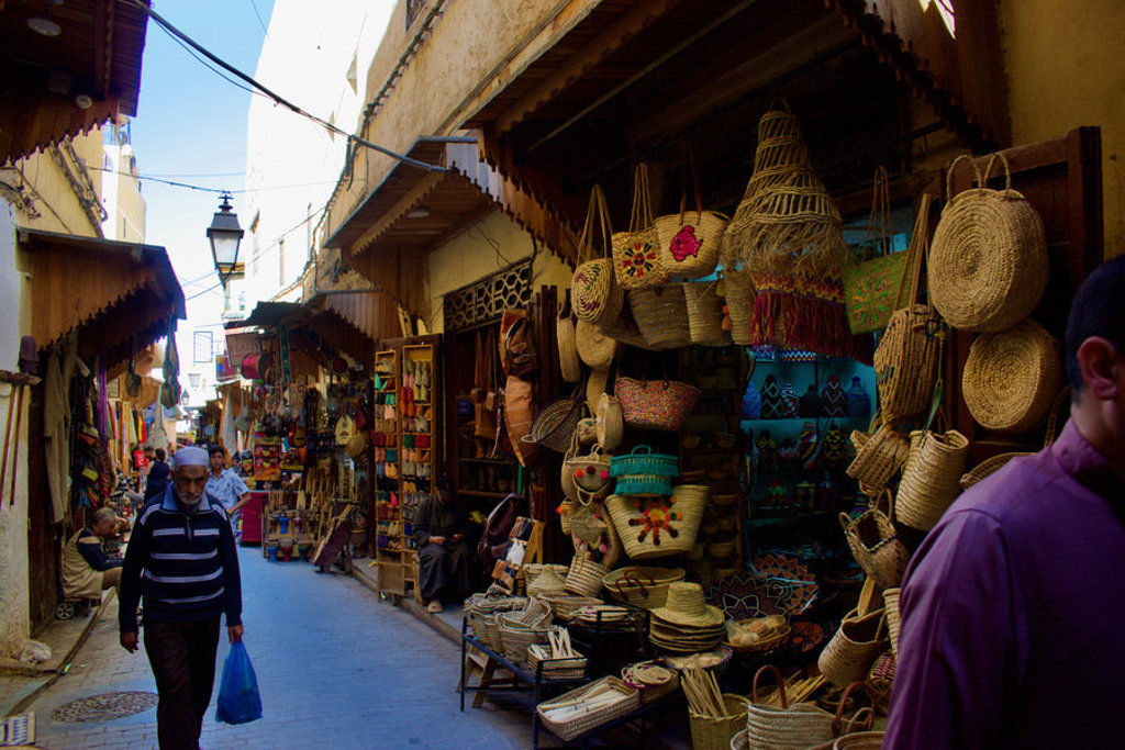 Smalle steeg in een Marokkaanse souk met winkels vol rieten manden en kleurrijke handwerken.
