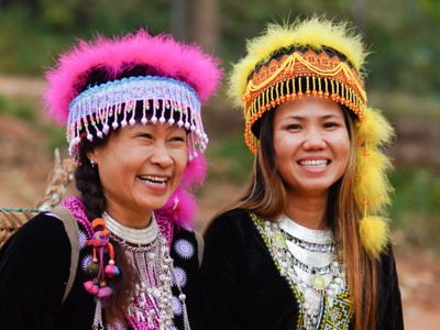 Portret van twee lachende vrouwen in traditionele kleding met kleurrijke hoofdtooien tijdens de route Thailand, Laos & Cambodja.