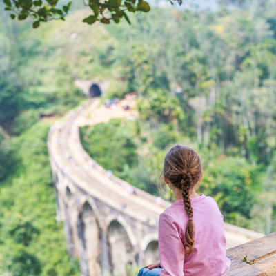 Meisje kijkt uit over de Nine Arches Bridge in Sri Lanka tijdens een familiereis.