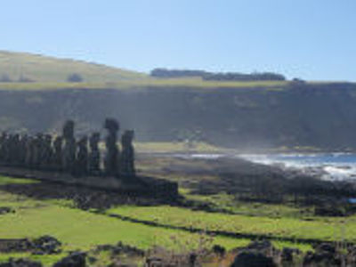 Moai-standbeelden van Ahu Tongariki op Paaseiland met groene velden en de oceaan op de achtergrond.