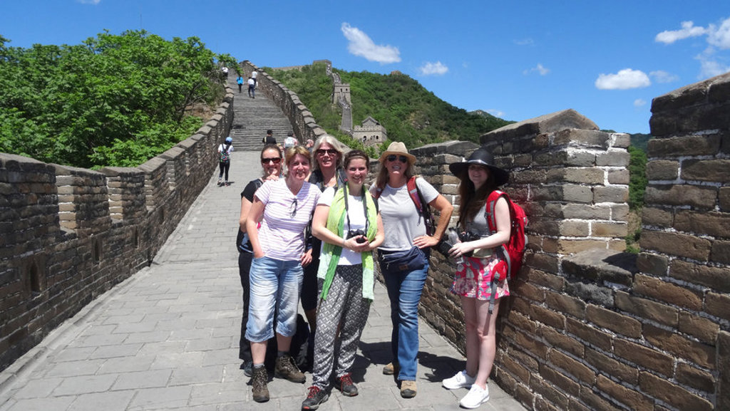 Groepsrondreis China: reizigers op de Chinese Muur met groen berglandschap en blauwe lucht.