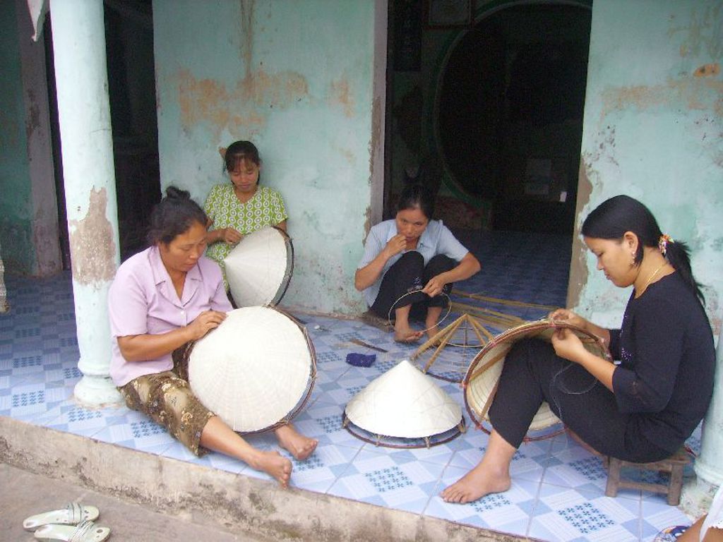 Vrouwen in Vietnam maken traditionele conische hoeden (nón lá) met bamboe en riet in een werkplaats.