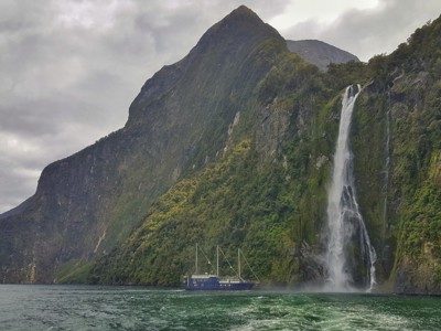 Boot bij een hoge waterval in Milford Sound, Nieuw-Zeeland.