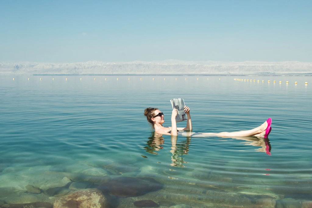 Reiziger drijft in de Dode Zee in Jordanië en leest een krant.
