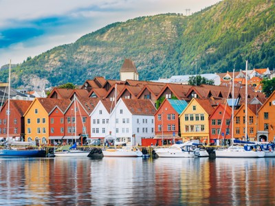 Gekleurde houten huizen aan de haven van Bergen met zeilboten en bergen op de achtergrond, Noorwegen.