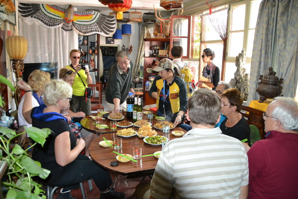 Reizigers tijdens een groepsrondreis China delen een maaltijd aan een ronde tafel in een lokaal restaurant.