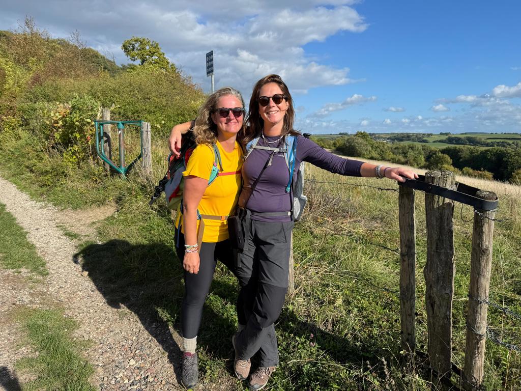 Twee wandelaars met rugzak op de Dutch Mountain Trail, met uitzicht over heuvels en dalen in Zuid-Limburg.