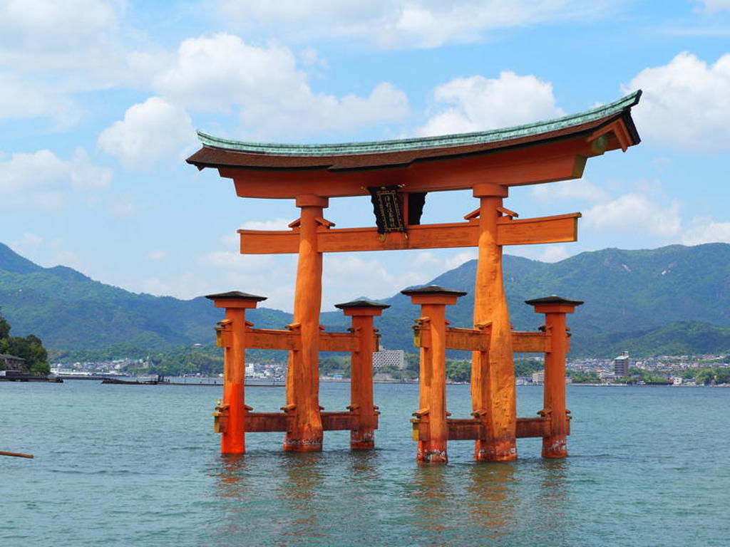 Rode torii-poort in zee bij Miyajima, Japan, tijdens een groepsrondreis.