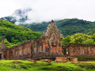 Wat Phou-tempelruïnes bij Champasak in Zuid-Laos, met groene bergen en mist op de achtergrond.