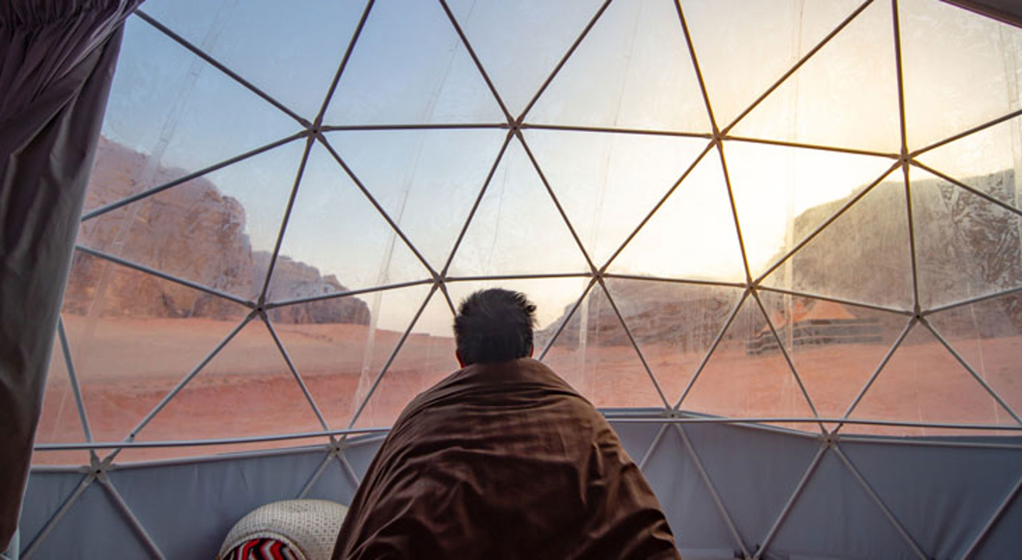 Uitzicht op de Wadi Rum-woestijn in Jordanië vanuit een transparante koepeltent bij zonsopkomst.