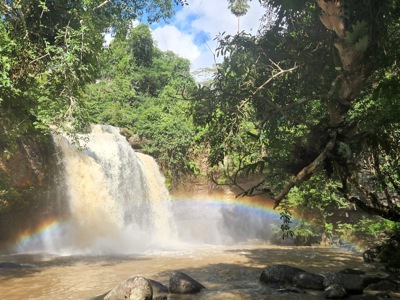 Waterval in het groene regenwoud van Thailand met een regenboog in de nevel.