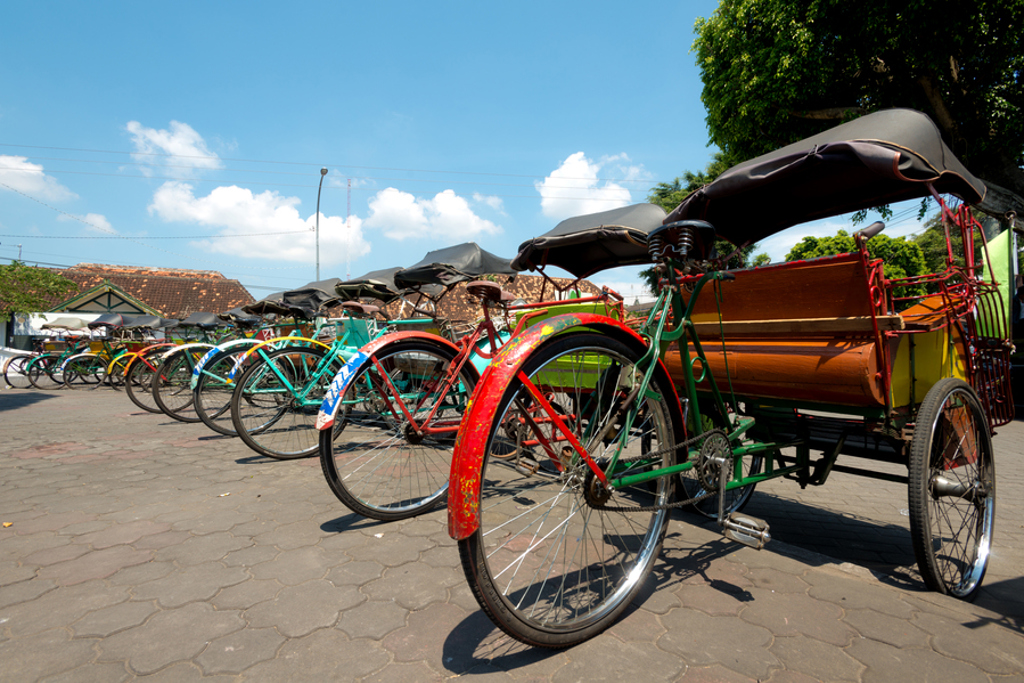 Rij kleurrijke becaks (fietstaxi’s) op een plein tijdens familiereis Java en Bali.