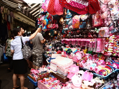 Drukke markt in Zuid-Korea met kraampjes vol kleurrijke tassen, haaraccessoires en souvenirs.