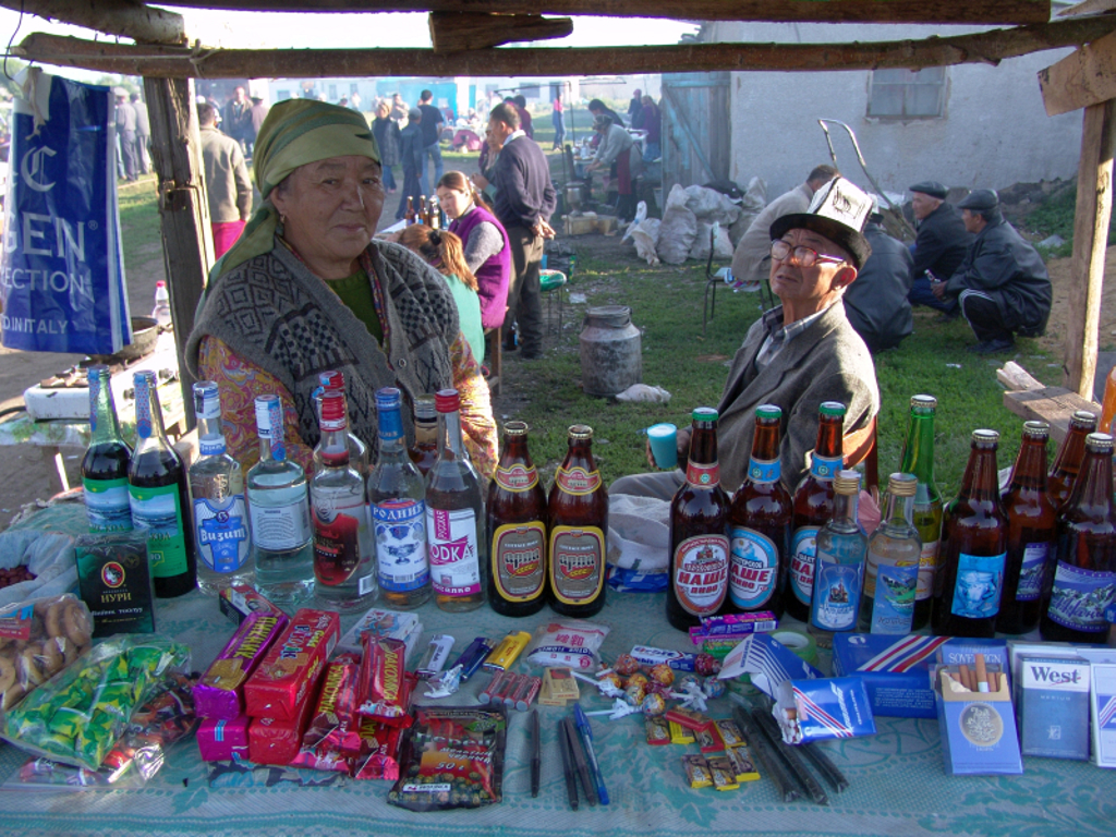 Marktkraam in Kirgistan met lokale verkopers en flessen drank en snacks tijdens groepsrondreis Kirgizië.