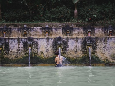 Heilige bronnen van Tirta Empul op Bali met waterfonteinen en badende bezoeker tijdens de Route Java en Bali.