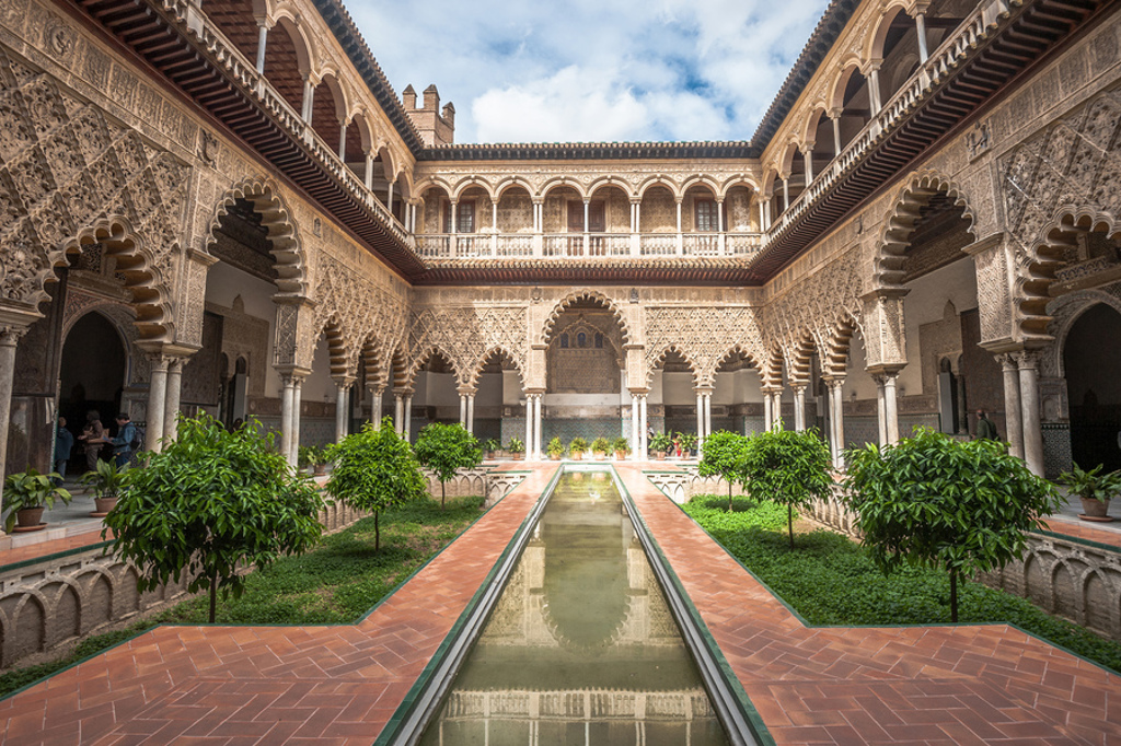 Binnenplaats met Moorse bogen en waterpartij in het Alcázar van Sevilla tijdens een 22-35ers reis door Andalusië.