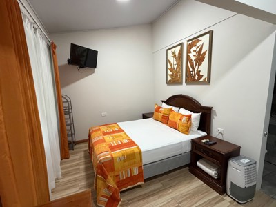Slaapkamer in Eco Arenal, Costa Rica, met tweepersoonsbed, oranje bedsprei en nachtkastjes.