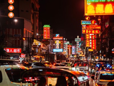 Drukke straat in Chinatown Bangkok met neonreclames en avondverkeer tijdens Route Thailand.