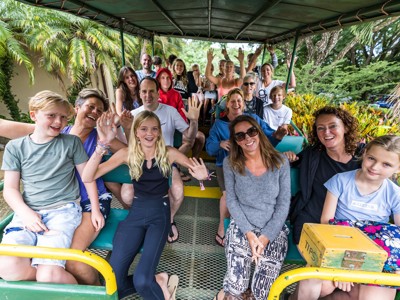 Reisgroep in een open trammetje tijdens de Route Costa Rica, zwaaiend naar de camera.