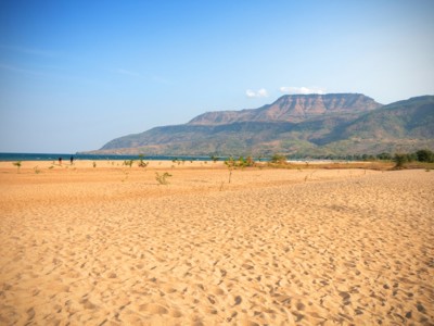 Zandstrand aan het Malawimeer met berglandschap op de achtergrond, route Zambia, Malawi en Tanzania.
