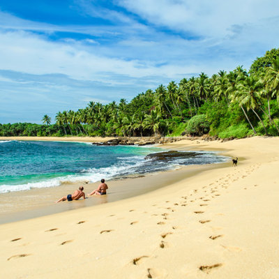 Tropisch zandstrand in Sri Lanka met palmbomen en turkoois water, populair strandmoment tijdens familiereis.