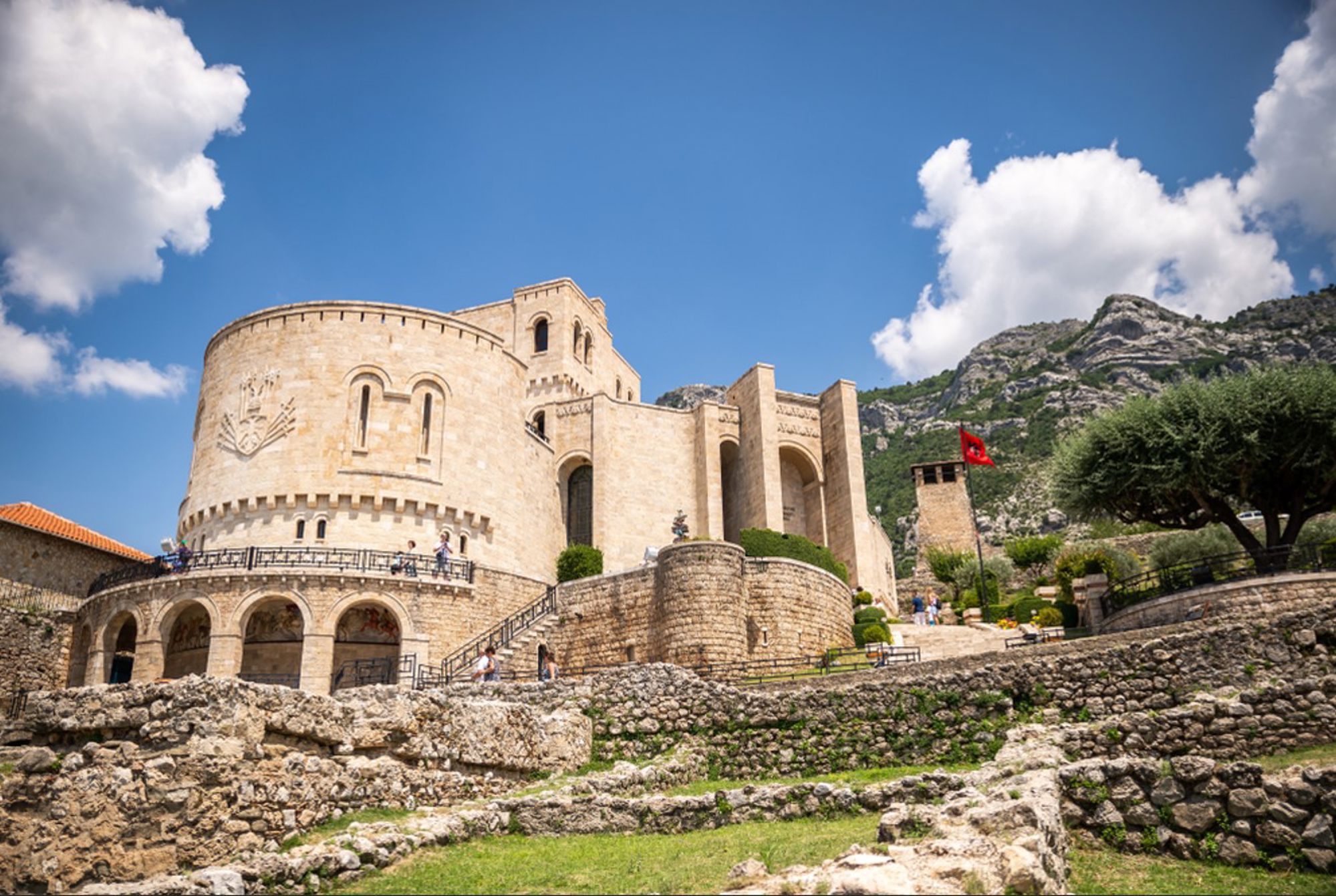 Rozafa-kasteel in Shkodër, Albanië, met stenen muren en Albanese vlag tegen bergen en blauwe lucht.