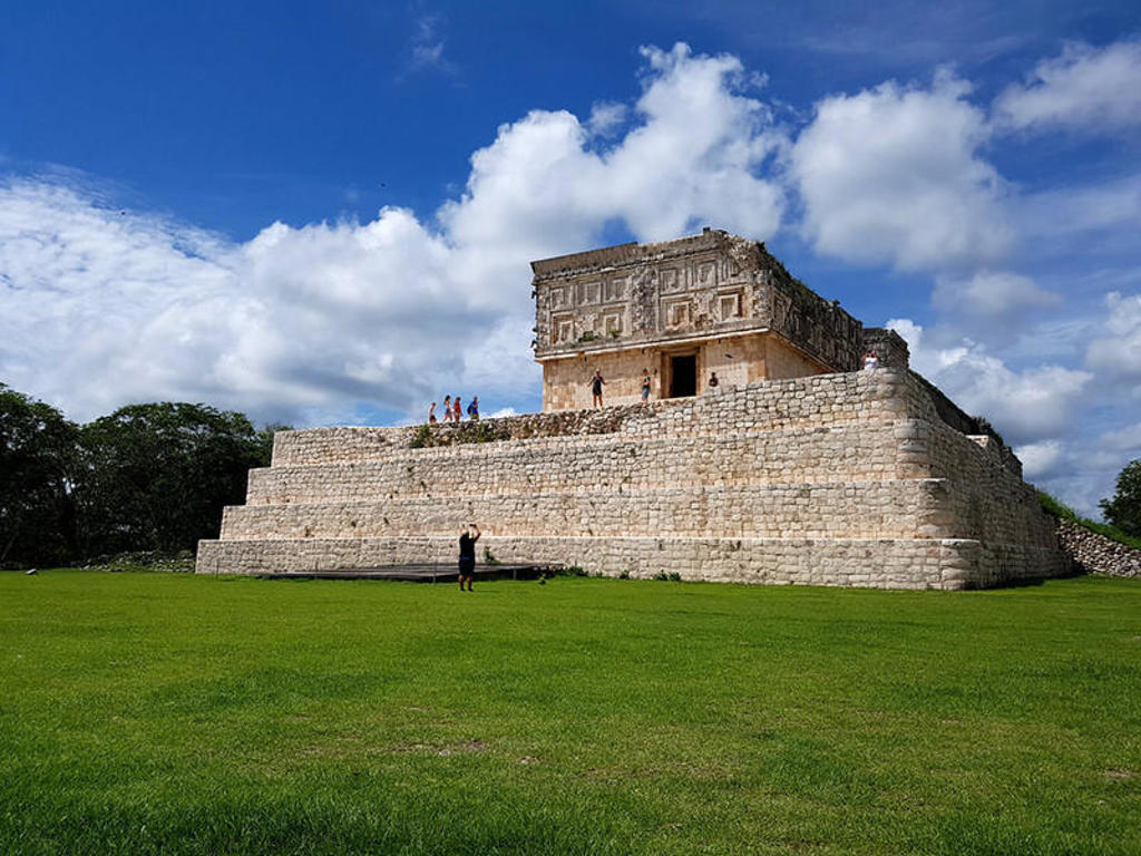 Piramide met tempel in Uxmal, Mexico, onder een blauwe lucht met wolken.