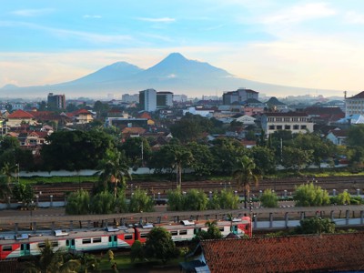 Skyline van Yogyakarta met treinspoor en de vulkaan Merapi op de achtergrond.