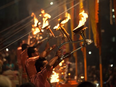 Avondceremonie met priesters die brandende olielampen omhooghouden aan de Ganges in Varanasi, Route India.