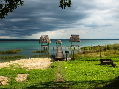 Houten steiger met rieten hutjes aan het turquoise water van Lago Petén Itzá, Guatemala.