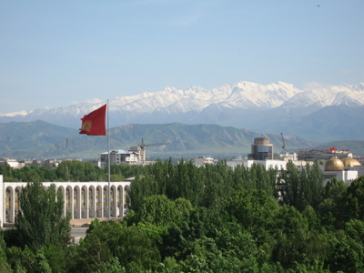 Uitzicht op Bisjkek met de Kirgizische vlag en besneeuwde Tian Shan-bergen op de achtergrond.