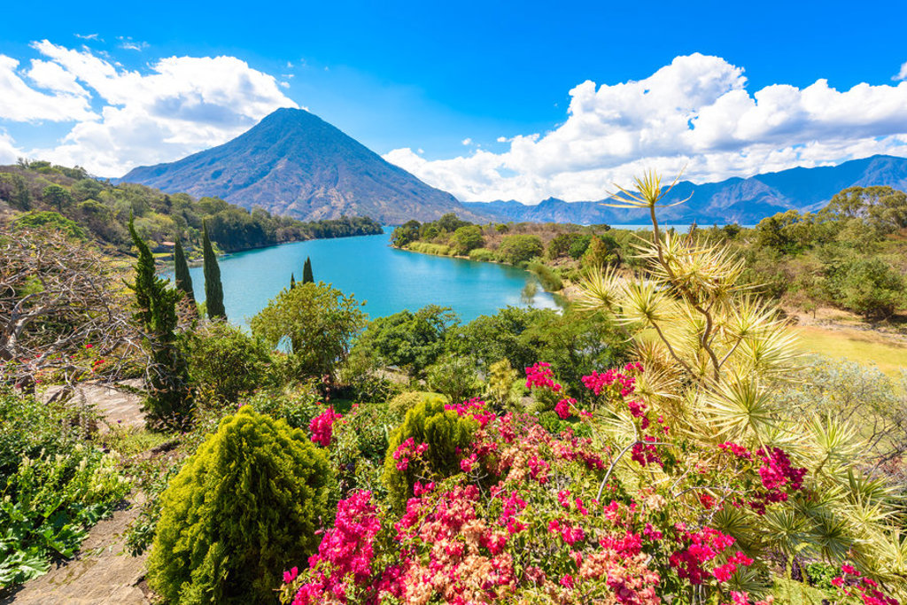 Uitzicht op het Atitlánmeer met vulkaan en kleurrijke bloemen in Guatemala.