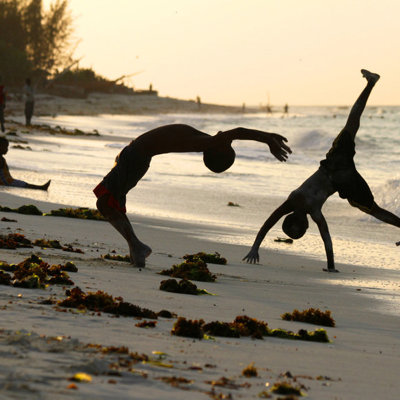 Kinderen maken salto’s op het strand bij zonsondergang op Zanzibar tijdens een familiereis Kenia, Tanzania & Zanzibar.