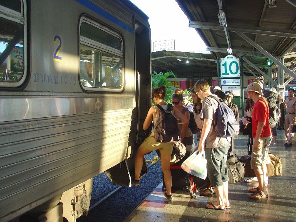 Reizigers stappen met bagage in de trein op een station in Thailand tijdens een familiereis Noord en Zuid.