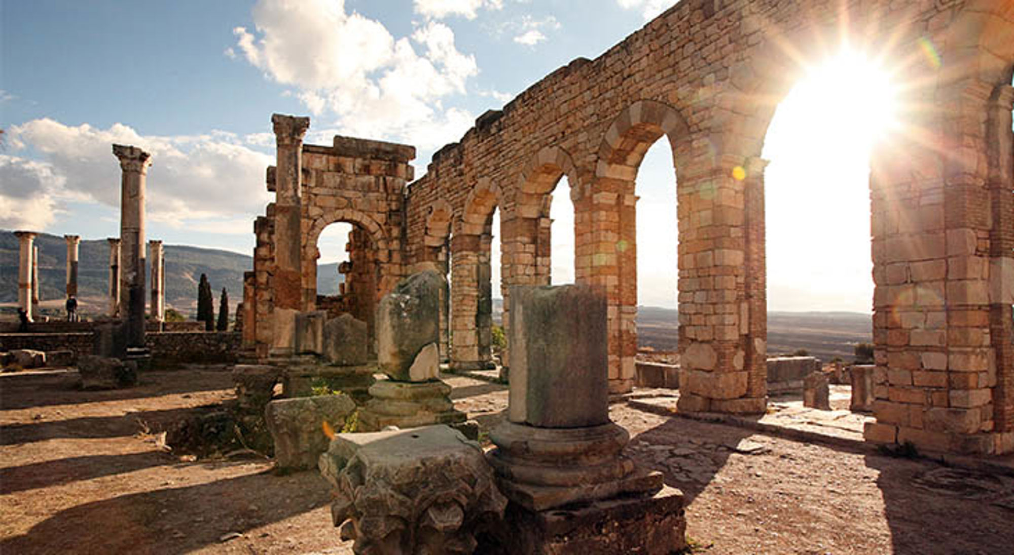 Romeinse ruïnes van Volubilis in Marokko, met stenen bogen en zuilen in de zon.