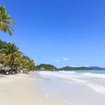 Tropisch zandstrand met palmbomen en ruisende golven tijdens groepsrondreis West-Maleisië & Borneo.